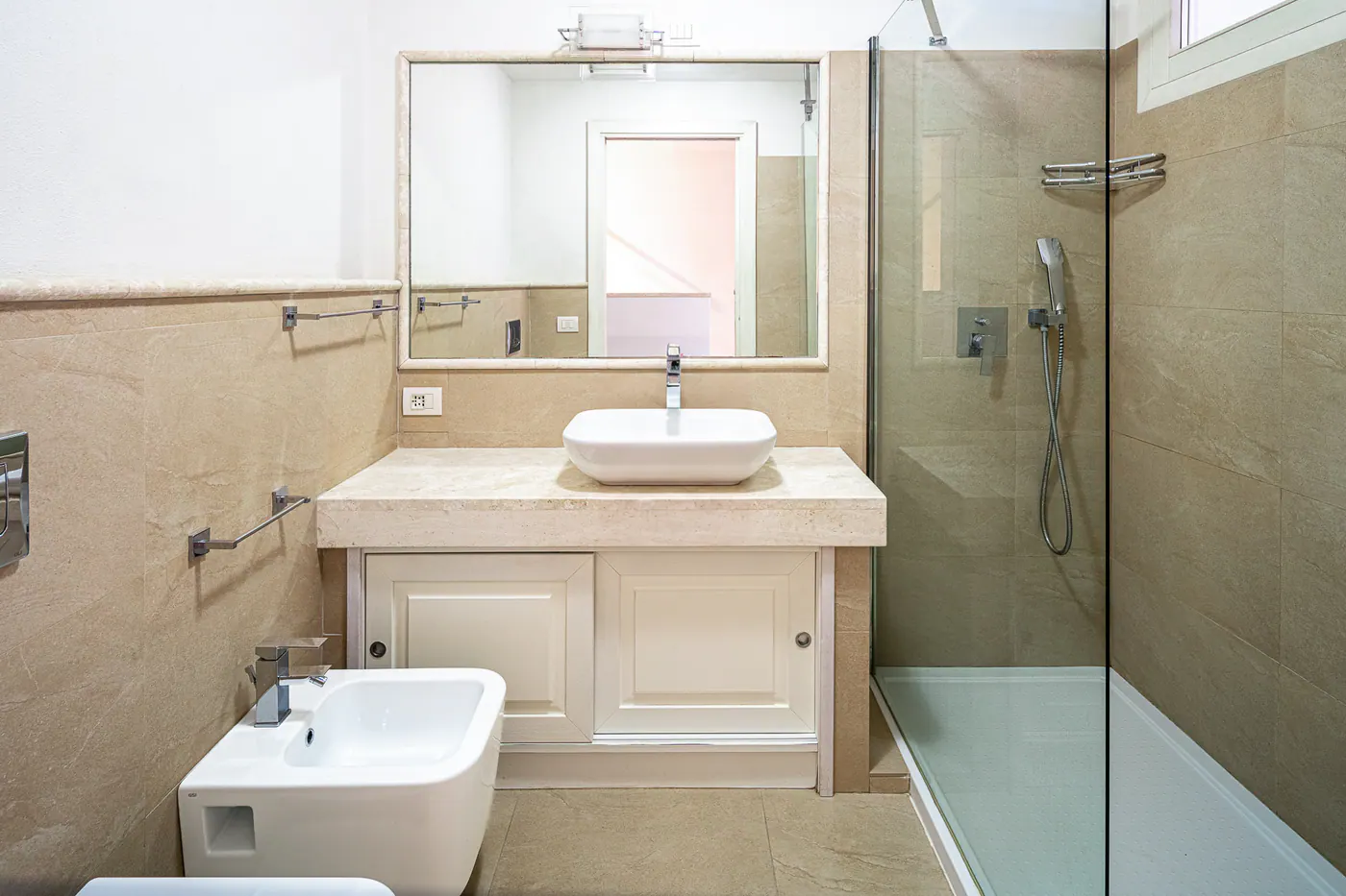 Second bathroom with glass shower, countertop basin and bidet