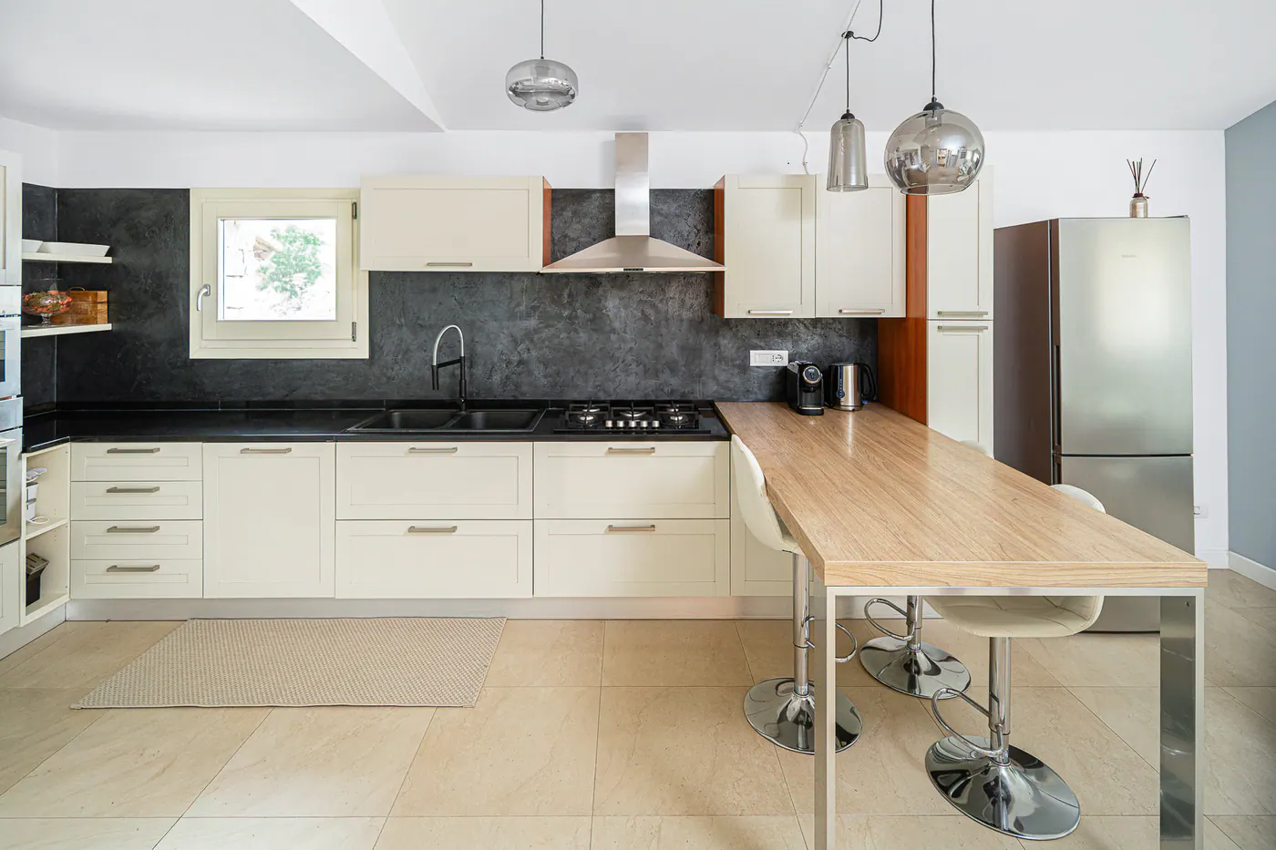 The kitchen with the wooden counter, stools and dark worktop