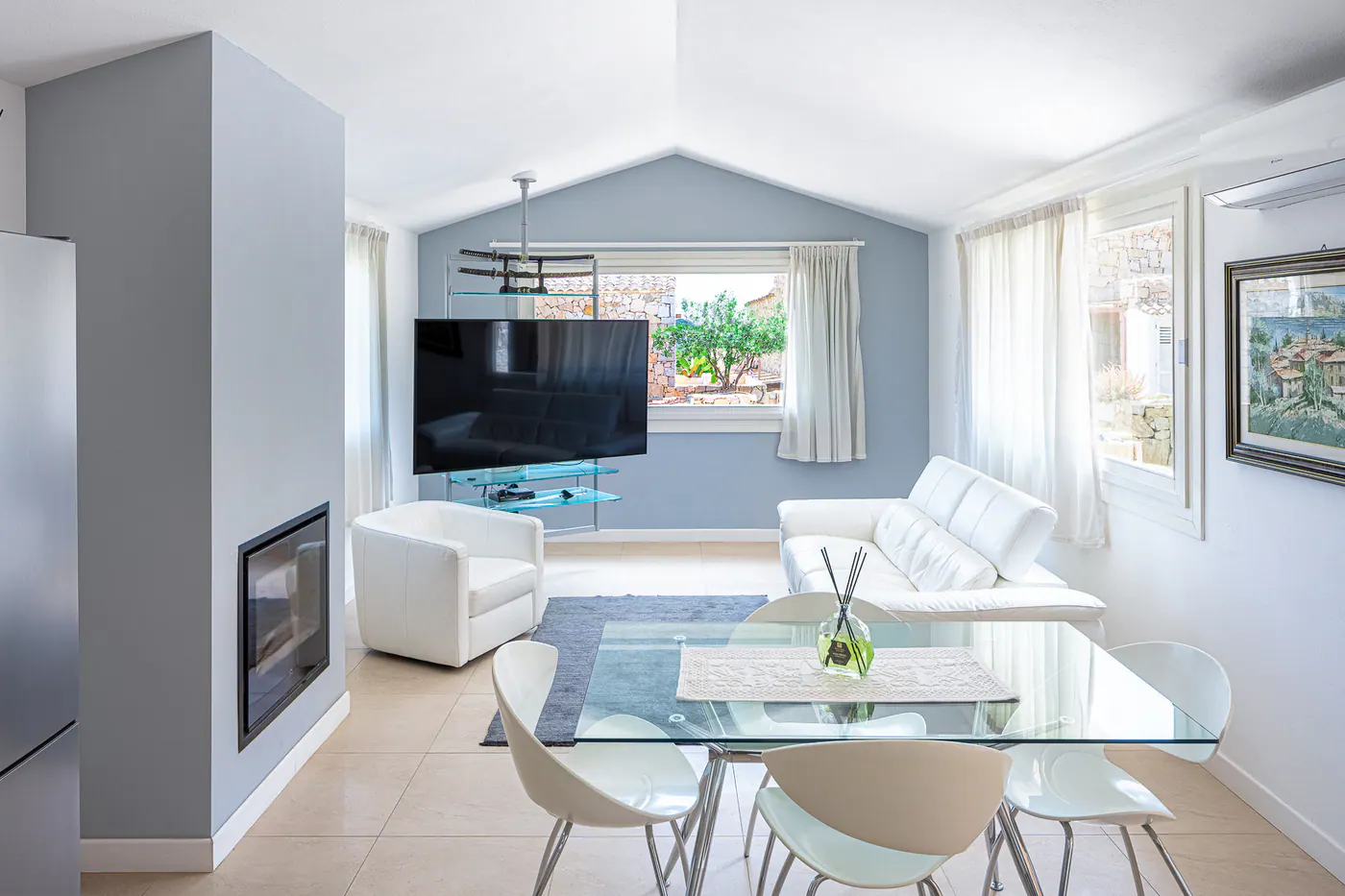 Living room with fireplace, white sofa and glass dining table