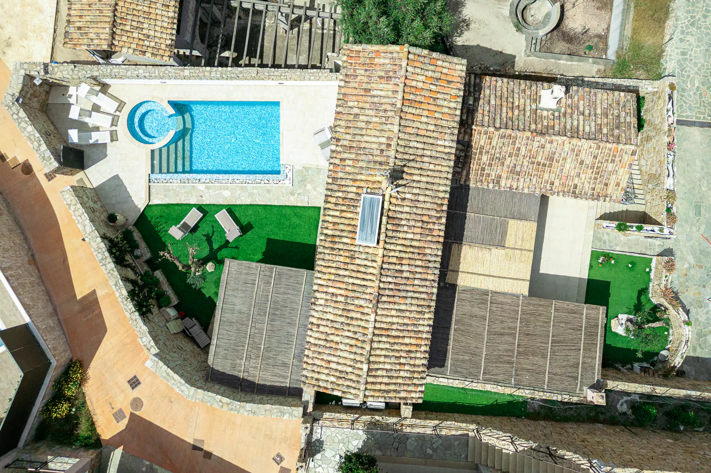 Pool, garden and villa roofs seen from a drone